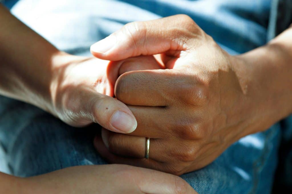 Two hands holding each other tightly for support